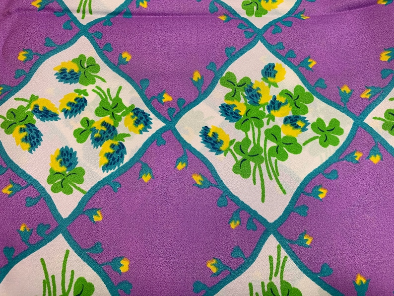 Pu&ograve; includere: Tessuto viola con un motivo di trifoglio bianco e verde. Il trifoglio &egrave; contornato di blu turchese e ha centri gialli.