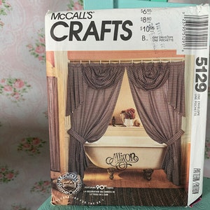 Op de afbeelding: Een naaipatroon voor een badkamergordijn met een gerimpelde bovenkant. Het patroon is van McCall's Crafts en heeft een bruin en wit gestreept stof. Het patroonnummer is 5129.