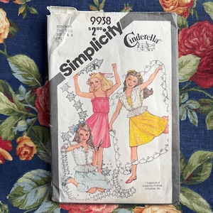 Pode incluir: Um padrão de costura Simplicity vintage para vestidos de menina. O padrão apresenta ilustrações de três meninas em vestidos diferentes. O número do padrão é 9938 e inclui tamanhos 7 e 8.