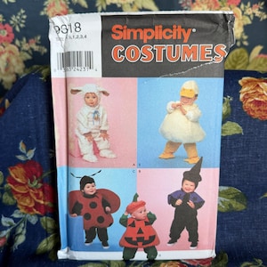 May include: A Simplicity Costumes sewing pattern envelope for infants, featuring illustrations of five different outfits: a white lamb, a yellow duck, a red ladybug, an orange pumpkin, and a black witch or wizard costume with a pointed hat.