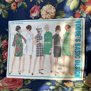 May include: A vintage Vogue's Basic Design sewing pattern from 1971. The pattern features five different dress designs, all with a simple, classic silhouette. The dresses are shown in a variety of colors and patterns, including green, black, white, and floral.