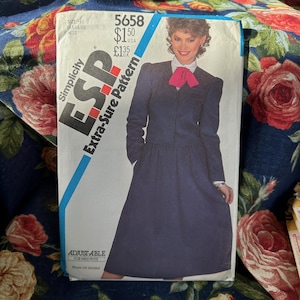 May include: A vintage Simplicity ESP Extra-Sure Pattern sewing pattern. The pattern features a woman wearing a navy blue suit with a white blouse and a pink bow. The pattern is adjustable for Miss Petite sizes.