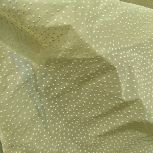 May include: A pale green fabric with a white polka dot pattern. The fabric is sheer and has a slightly textured surface.