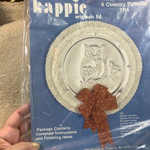 May include: A package of six country patterns for crafting. The package includes a pattern for a country owl design, a pineapple design, a country time gal design, a country rooster design, a country goose design, and a country pie design. The package contains complete instructions and finishing ideas. The patterns are from Rappie originals Itd. and are approximately 7 inches in diameter.