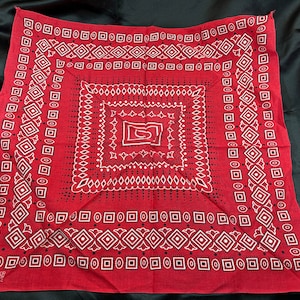 May include: Red bandana with a white geometric pattern. The bandana has the text "Fast Color 100% Cotton RN 13922" in the bottom left corner.
