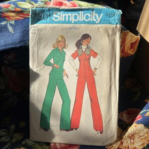 May include: Simplicity sewing pattern number 7301 for a two-piece outfit. The pattern is for sizes 8 to 14 and includes instructions for a green pantsuit and a red pantsuit.