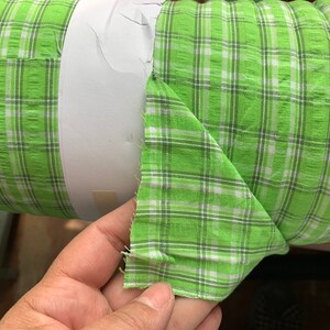May include: A roll of green and white checkered fabric. The fabric is folded in half and the edges are frayed.