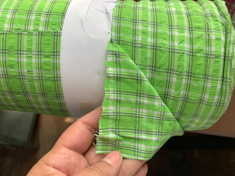 May include: A roll of green and white checkered fabric. The fabric is folded in half and the edges are frayed.