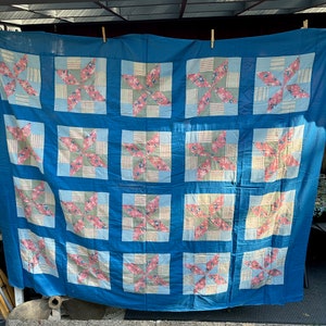 Pode incluir: Uma colcha de retalhos azul e rosa com um padrão de estrela. A colcha é feita de quadrados de tecido costurados juntos para criar um design maior.