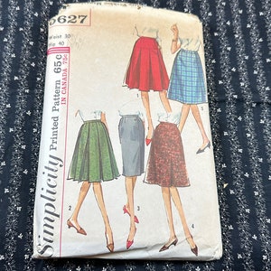 Könnte beinhalten: Vintage Simplicity Schnittmuster mit Rockdesigns. Das Muster zeigt Illustrationen verschiedener Rockstile in Rot, Grün, Grau und gemusterten Stoffen. Das Muster ist mit "65c in Canada 75c" gekennzeichnet.