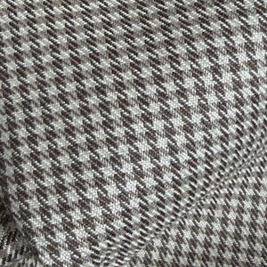 May include: Close-up of a fabric with a houndstooth pattern. The fabric features a repeating pattern of small, four-pointed shapes in shades of brown and white. The texture appears to be woven, with visible threads creating a subtle, textured surface.