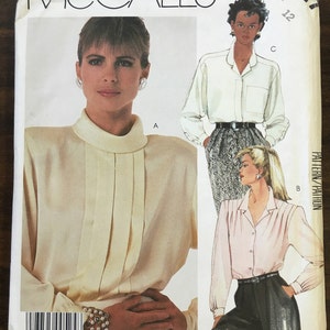 May include: A sewing pattern for a blouse with a high collar and long sleeves. The pattern is by McCall's and is designed by Liz Claiborne. The pattern includes three different views of the blouse.