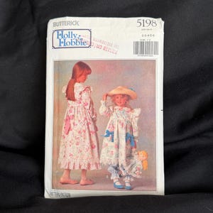 Könnte beinhalten: Ein Vintage-Schnittmuster von Butterick mit einem Holly Hobbie-Design. Das Muster zeigt zwei junge Mädchen in Blumenkleidern und Hosen. Die Musternummer ist 5198, mit den Größen 2-3-4-5-6. Das Muster befindet sich auf schwarzem Hintergrund.