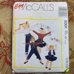Puede incluir: Un patrón de costura para ropa de niños, con tres niñas que llevan diferentes atuendos. El patrón se llama "Jumping Beans" y es de talla 4, 5 o 6. El patrón es de McCall's.