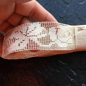 Puede incluir: Borde de encaje de algodón blanco con un delicado patrón floral. El encaje tiene aproximadamente 2,5 cm de ancho y un borde festoneado.
