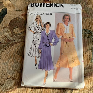 Puede incluir: Un patrón de costura Butterick vintage con ilustraciones de tres vestidos diferentes. El paquete del patrón tiene el texto "DAVID WARREN" y "(8-10-12)". Los vestidos incluyen un vestido de lunares, un vestido morado y un vestido amarillo.