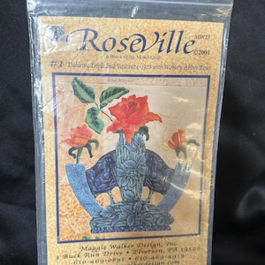 May include: A vintage-style quilt pattern featuring a triple bud vase with three red roses. The pattern is titled "Roseville #1 Dahlrose Triple Bud Vase 1924-1928 with Woburn Abbey Roses" and is a "Block of the Month Quilt". The pattern is copyrighted 2001.