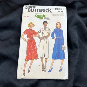 May include: A vintage Butterick sewing pattern, size 16, featuring illustrations of three dresses. The pattern includes a red floral dress, a white dress, and a blue dress. The pattern's cover has the text "QUICK! BUTTERICK" and "QUICK! TIP".