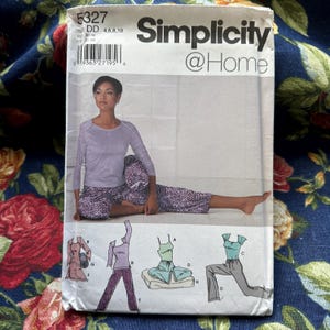 May include: Simplicity @Home sewing pattern featuring a woman wearing a long-sleeved lavender top and patterned pants. The pattern includes multiple outfit options, with illustrations of each design. The pattern's size is DD 4,6,8,10.