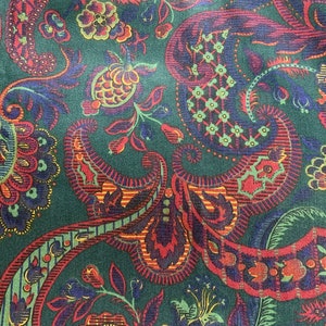 Könnte beinhalten: Ein grüner Stoff mit einem Paisley-Muster in Rot-, Blau- und Gelbtönen. Das Muster ist kompliziert und zeigt eine Vielzahl von floralen und Paisley-Motiven.