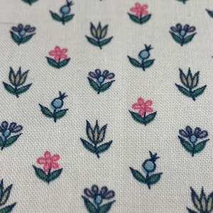 May include: White fabric with a repeating pattern of small blue, pink, and yellow flowers. The flowers are stylized and have a simple design.