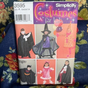 Könnte beinhalten: Eine Simplicity-Schnittmusterhülle 3595 für Kinderkostüme in Größe A mit Abbildungen von Kindern in verschiedenen Outfits, darunter ein schwarzer Umhang, ein Hexenkostüm, ein gemustertes Kleid, ein Fledermaus-Outfit, ein rosa Kleid und ein Vampirumhang.