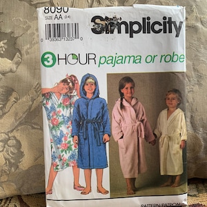 Può includere: Modello di cucito Simplicity numero 8090 per un pigiama o una vestaglia. Il modello è per le taglie AA (2-4). La copertina del modello mostra quattro bambini che indossano vestaglie di diversi colori.