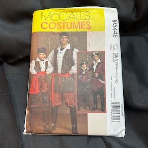 May include: A sewing pattern for a pirate costume. The pattern includes instructions for making a pirate coat, pants, and hat. The pattern is for men's sizes small, medium, large, and extra large. The pattern number is M5446.