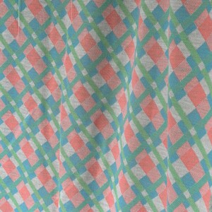 Puede incluir: Primer plano de una tela a cuadros rosa y azul sobre fondo blanco. La tela est&aacute; doblada y tiene un aspecto suave y texturizado.