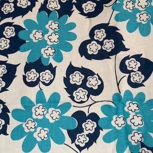 May include: A white fabric with a repeating pattern of blue and dark blue stylized flowers. The flowers have white centers and are surrounded by dark blue leaves.