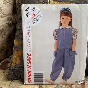 May include: A McCall's Stitch 'N Save sewing pattern for a child's jumpsuit. The pattern features a young girl wearing the jumpsuit, which has a button-up front, pockets, and bow details. The pattern size is B (4-5-6).