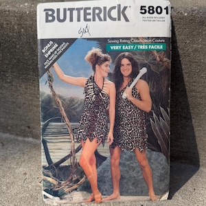May include: Butterick sewing pattern 5801 with a costume design. The cover displays two people in leopard print outfits, one holding a bone club. The text includes "Very Easy" and "Bonus Face Make-Up Designs".