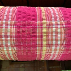May include: Red, white, and yellow plaid fabric with a textured surface.