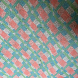 Puede incluir: Primer plano de una tela a cuadros rosa, verde y azul. La tela tiene una textura tejida y un patr&oacute;n diagonal.