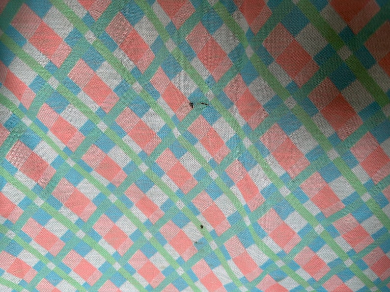 Puede incluir: Primer plano de una tela a cuadros rosa, verde y azul. La tela tiene una textura tejida y un patr&oacute;n diagonal.