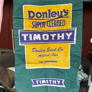 Peut inclure: Sac de semences vert et jaune avec le texte "Donley's Brand Super-Cleaned Timothy" et "Donley Seed Co. Ashland, Ohio 1 Bu. When Packed Timothy".