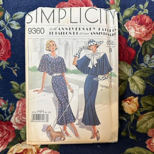May include: Simplicity sewing pattern number 9360 for a dress with a cape. The pattern is for sizes 6-12 and is a 60th anniversary pattern. The pattern shows two women wearing the dress, one with a polka dot hat and the other with a white collar.