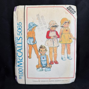 Może przedstawiać: Vintage wzór krawiecki McCall's 5065 na sukienki, kombinezony, pajacyki i kapelusze dla małych dzieci. Okładka wzoru zawiera ilustracje dzieci w różnych strojach. Cena to 1,00 $. Wzór jest dla rozmiarów dla małych dzieci.