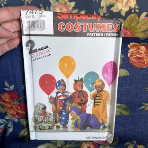May include: A Simplicity Costumes sewing pattern envelope, number 7475, size A (1/2-4), from the 2 Hour Express collection. The front features illustrations of children in various costumes including a clown, pumpkin, bee, and grape, with balloons.