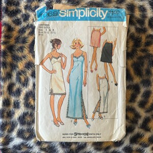 Puede incluir: Sobre de patrón de costura Simplicity vintage. El sobre presenta ilustraciones de vestidos y faldas. El texto en el sobre incluye "Simplicity", "Talla 6 y 8" y "Stretch Knits Only". El sobre está sobre un fondo de estampado de leopardo.