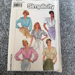 Może przedstawiać: Koperta wykroju Simplicity z ilustracjami damskich bluzek. Bluzki są w różnych stylach, w tym z długim rękawem, z krótkim rękawem i we wzory. Koperta zawiera logo Simplicity i szczegóły wykroju.