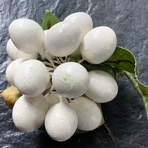 May include: A cluster of white, textured, faux berries with green leaves. The berries are arranged in a circular shape and have a slightly iridescent finish.