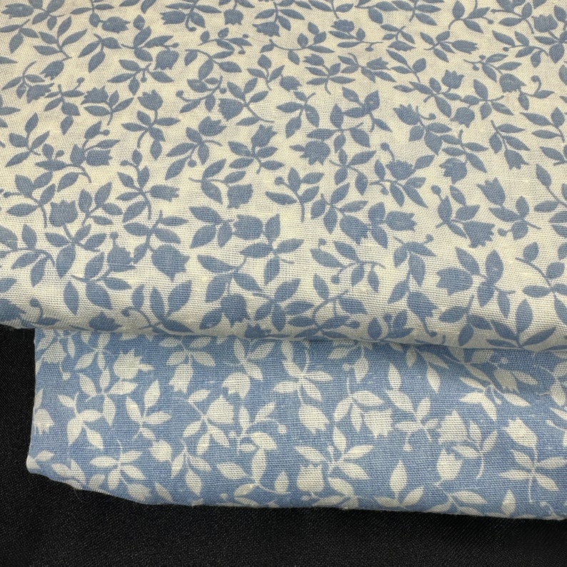 May include: Two pieces of blue and white fabric with a floral pattern. The fabric has a linen texture and features a repeating pattern of small blue flowers and leaves on a white background.