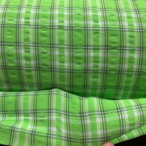 May include: Green and white plaid fabric with a textured weave.