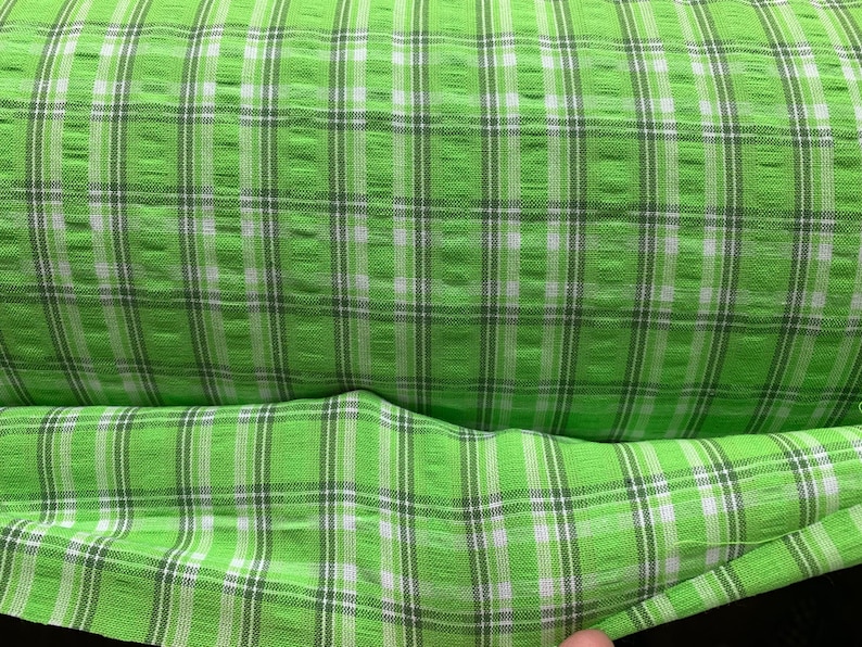 May include: Green and white plaid fabric with a textured weave.
