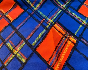 May include: Blue and red plaid fabric with a geometric pattern of black, yellow, and red lines.
