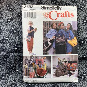 Könnte beinhalten: Simplicity Crafts Nähmuster Nummer 8852 zum Nähen von Taschen. Das Muster enthält Anleitungen zum Nähen einer Vielzahl von Taschen, darunter eine Einkaufstasche, eine Umhängetasche und ein Rucksack. Das Muster ist mit Fotos der fertigen Taschen illustriert.