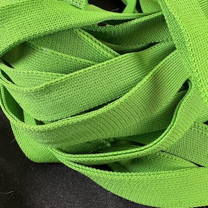May include: A close-up of a pile of bright green elastic bands. The bands are made of a soft, stretchy material and are perfect for crafts, hair ties, or other uses.