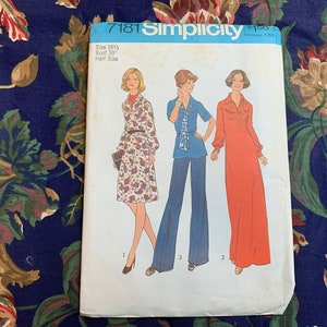 May include: Vintage Simplicity sewing pattern number 7181 for a dress and pants. The pattern is for sizes 16 1/2 and bust 39 inches. The pattern shows three women wearing the garments. The dress is a long, flowing style in a red color. The pants are wide-legged and blue. The dress has a long sleeve and a high neck. The pants have a short sleeve and a round neck.