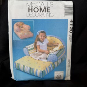 May include: McCall's Home Decorating pattern packet featuring a child's chair design. The packet shows a child sitting in a finished chair with a blue, yellow, and green striped pattern. The packet also shows a smaller chair with a floral pattern.